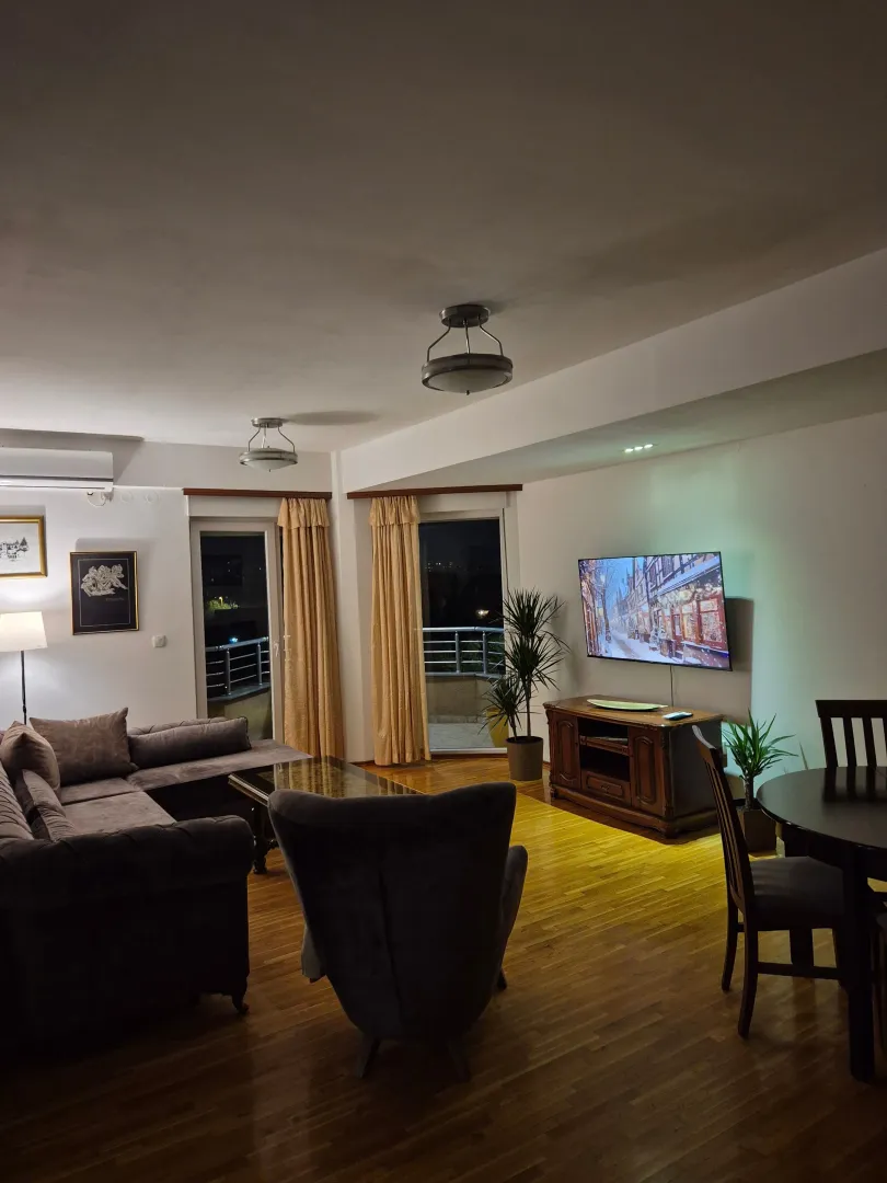 Spacious living room with sofa, TV and dining table.