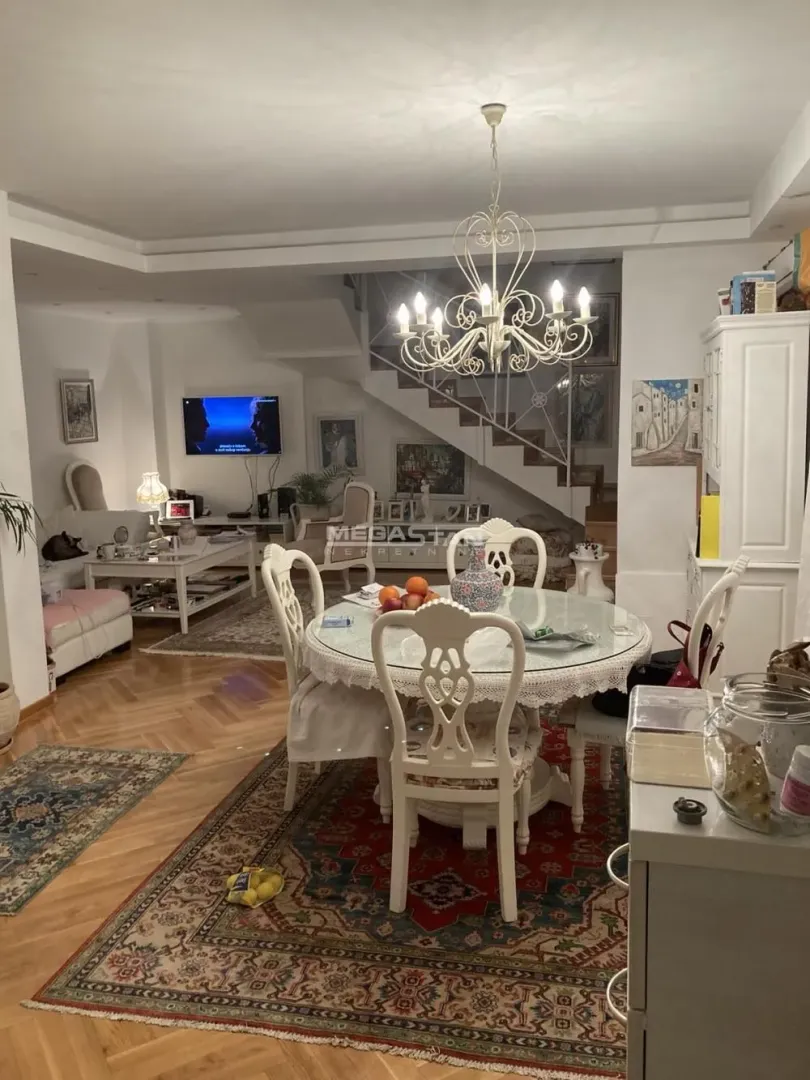Dnevna soba sa trpezarijskim stolom i stepeništem u pozadini.
