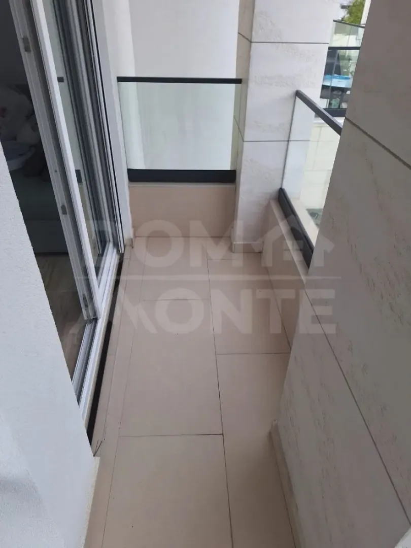 Small tiled balcony with glass railing and access from the apartment.