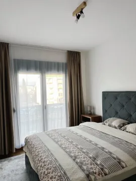 A furnished bedroom with a double bed and balcony doors. - image 9