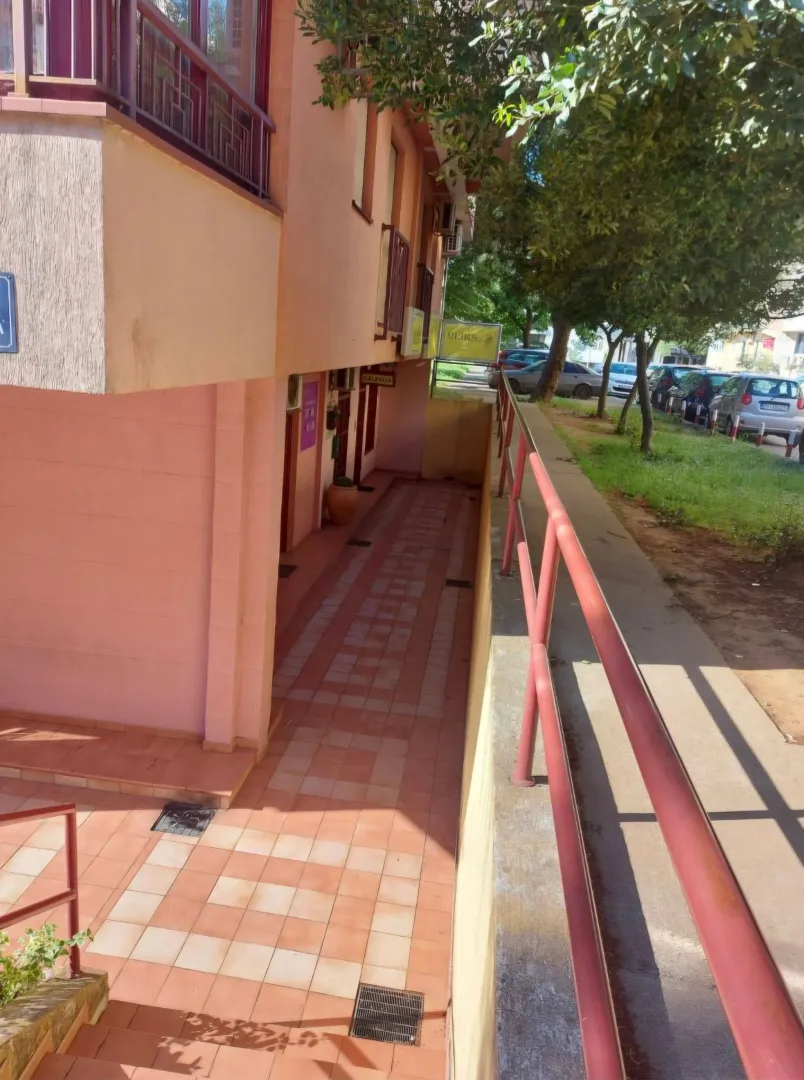 Exterior view of the building and entrance walkway with a railing.