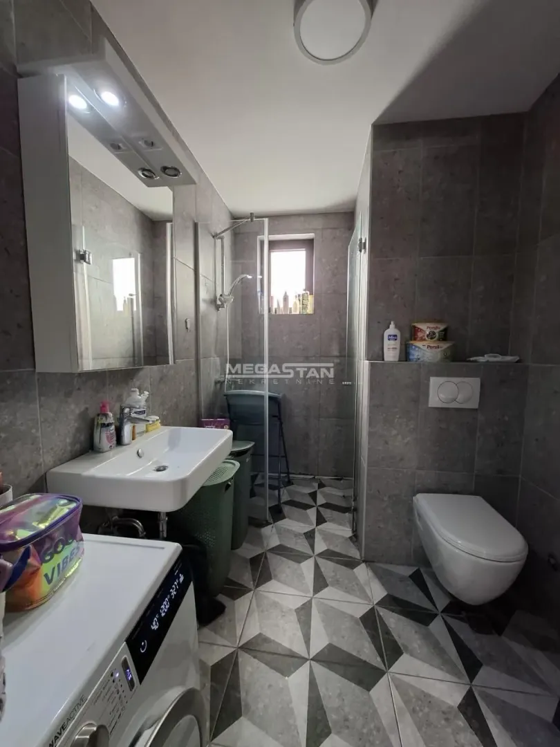 Modern bathroom with a walk-in shower, washbasin, toilet, and washing machine.