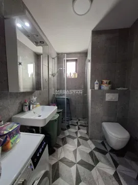 Modern bathroom with a walk-in shower, washbasin, toilet, and washing machine. - image 3