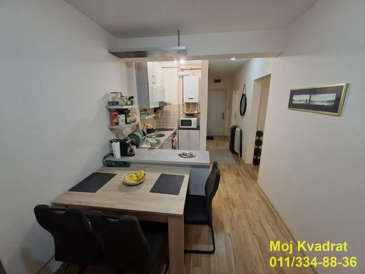 Manja kuhinja sa trpezarijskim stolom i stolicama u produžetku.