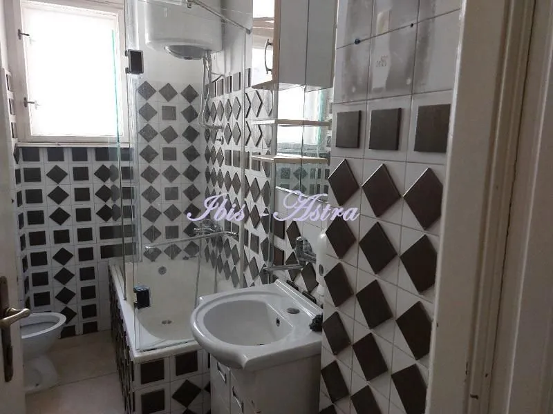 Bathroom with a bathtub, washbasin, and toilet, tiled with black and white tiles.