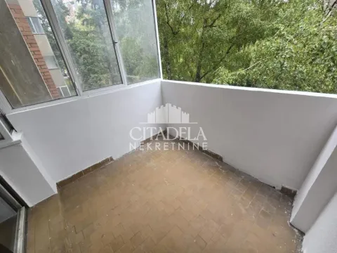 Zastakljeni balkon sa pogledom na zelenilo i okolne zgrade. - image 14