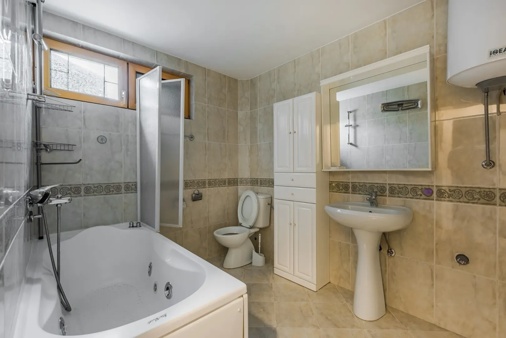 Bright bathroom featuring a jacuzzi tub, pedestal sink, and tall white cabinet.