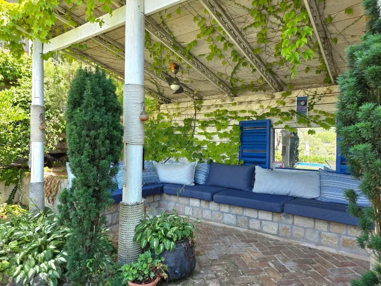 Natkrivena terasa sa garniturom za sjedenje i zelenilom.