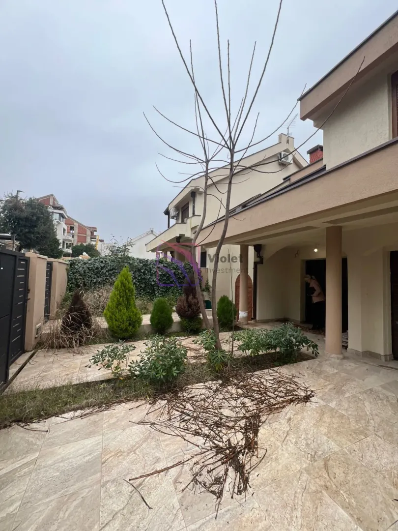 Pogled na dvorište i fasadu kuće sa uređenim vrtom.