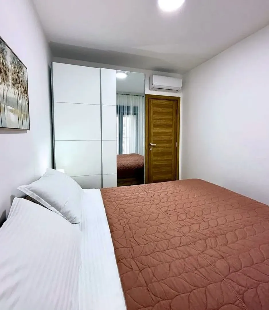 Furnished bedroom with a double bed, white wardrobe, and air conditioning.