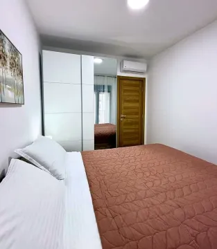Furnished bedroom with a double bed, white wardrobe, and air conditioning. - image 9