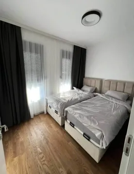Bedroom with two beds and dark curtains. - image 6