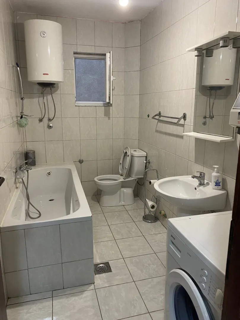 Simple bathroom with a bathtub, sink, and washing machine.