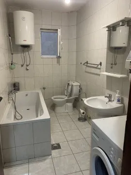 Simple bathroom with a bathtub, sink, and washing machine. - image 7
