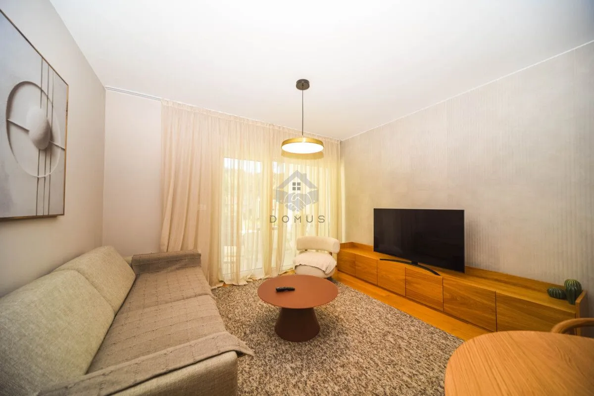 Living room with sofa, television, and dining table.