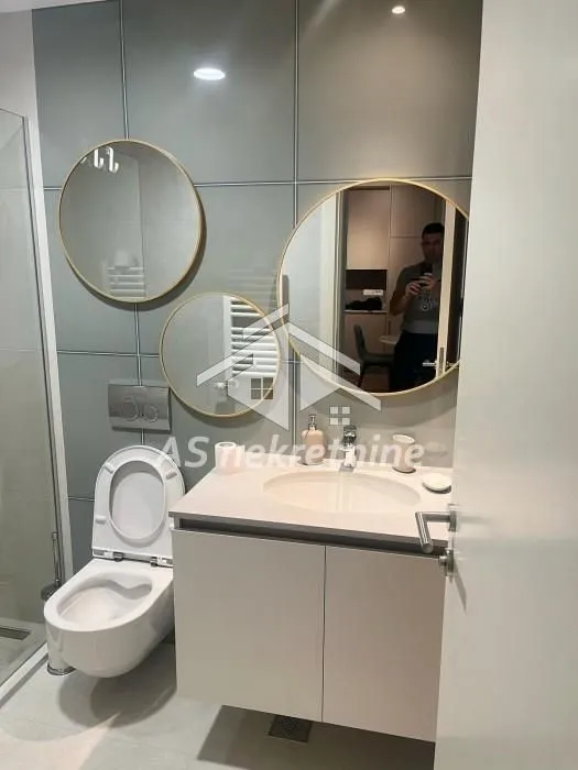 Modern bathroom with a washbasin, toilet, and decorative mirrors.