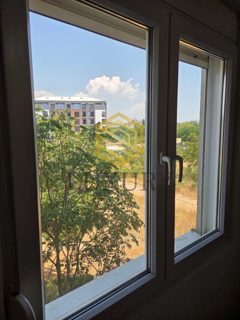 View through the window of surrounding greenery and buildings.