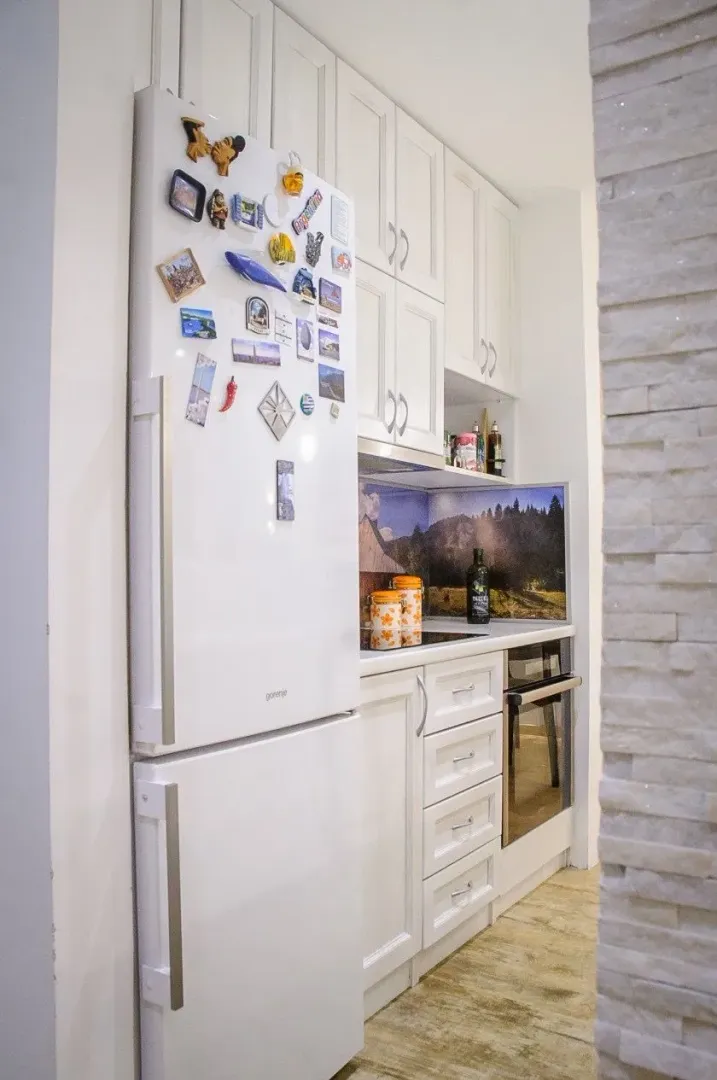 White kitchen with a white refrigerator and built-in appliances.