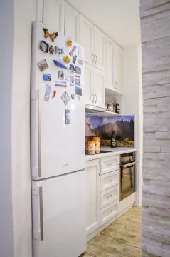 White kitchen with a white refrigerator and built-in appliances. - image 4
