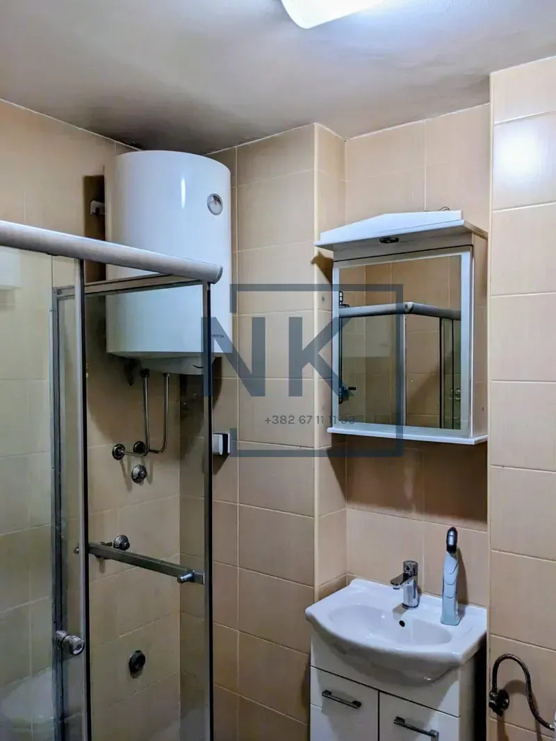 Bathroom with a shower cabin, washbasin, and water heater.