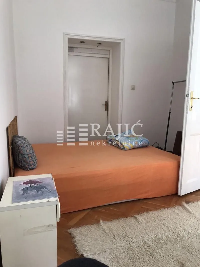 Smaller bedroom with a bed and parquet flooring.