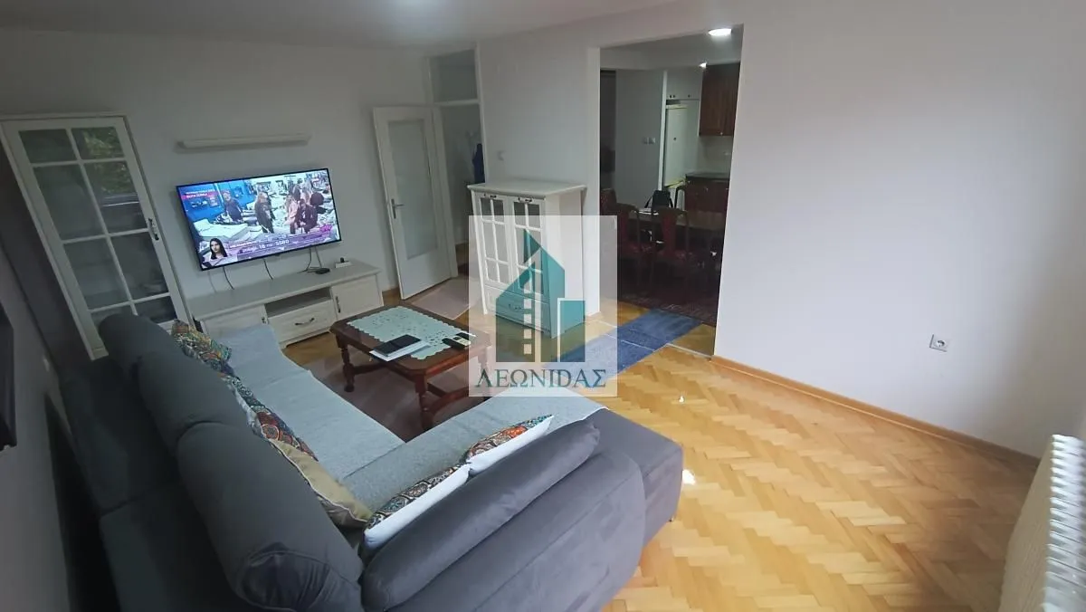 Living room with sofa, TV and view of the dining area.