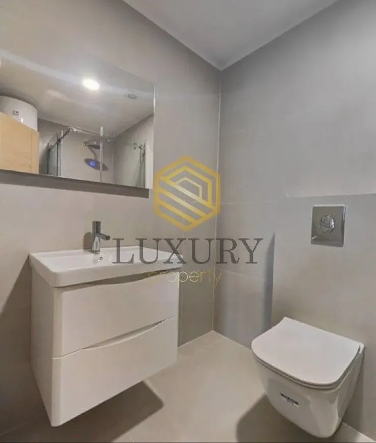 Modern bathroom with a washbasin, mirror, and toilet.