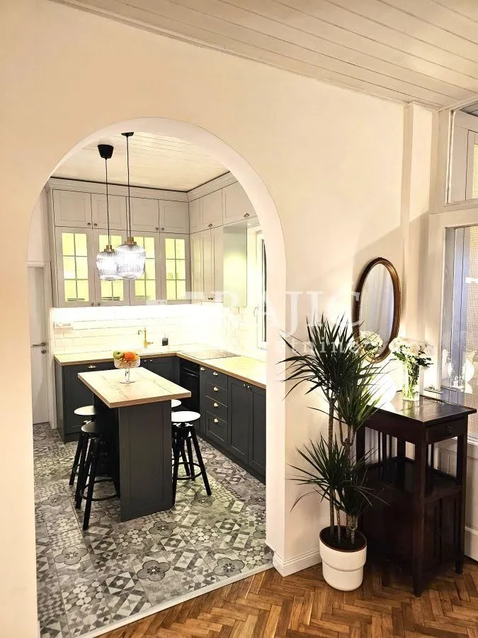 View from the hallway into a modern kitchen with an island through an arched doorway.