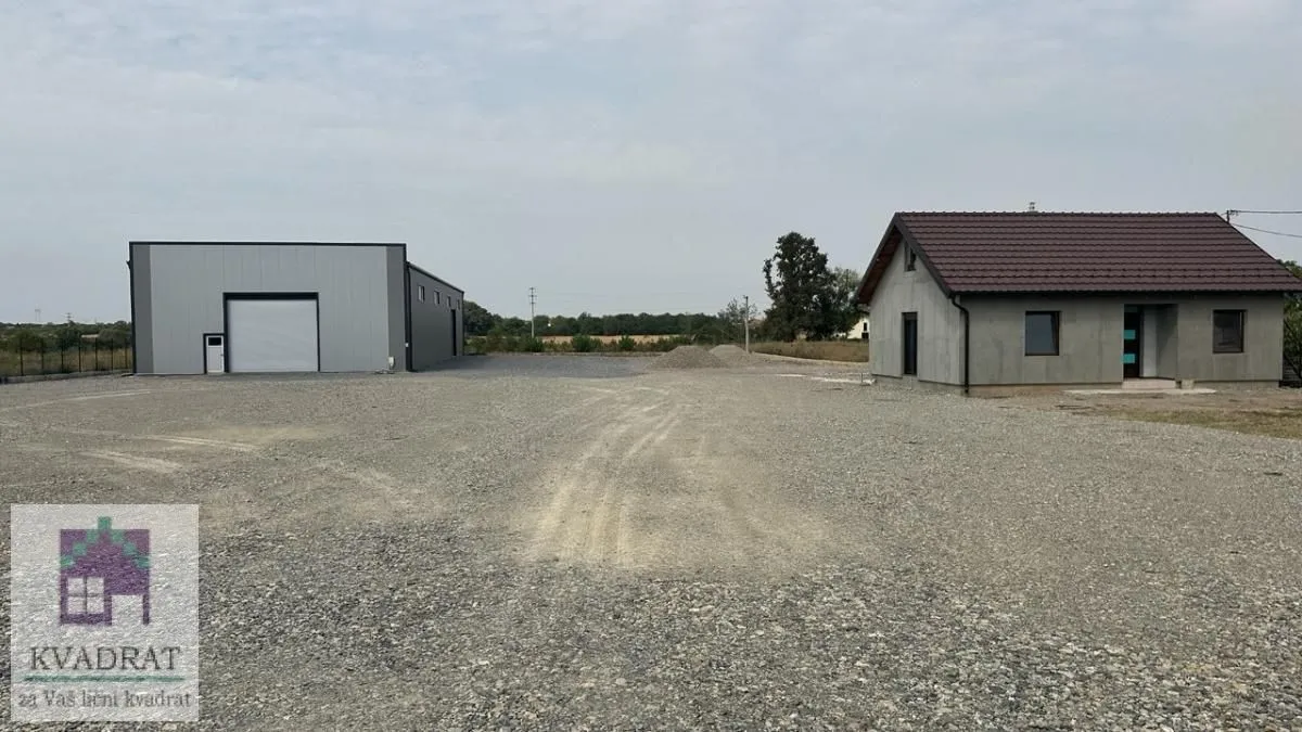 View of the yard with buildings and gravel ground.
