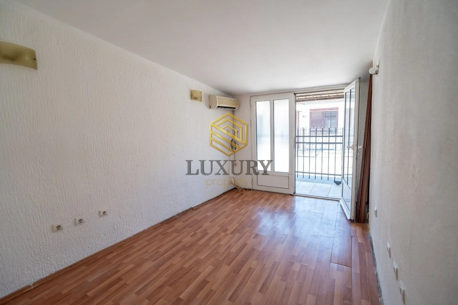 Empty room with laminate flooring and access to the terrace.