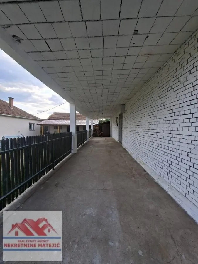 Covered porch and passageway next to the house with a white facade.