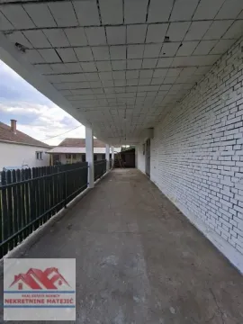 Covered porch and passageway next to the house with a white facade. - image 4