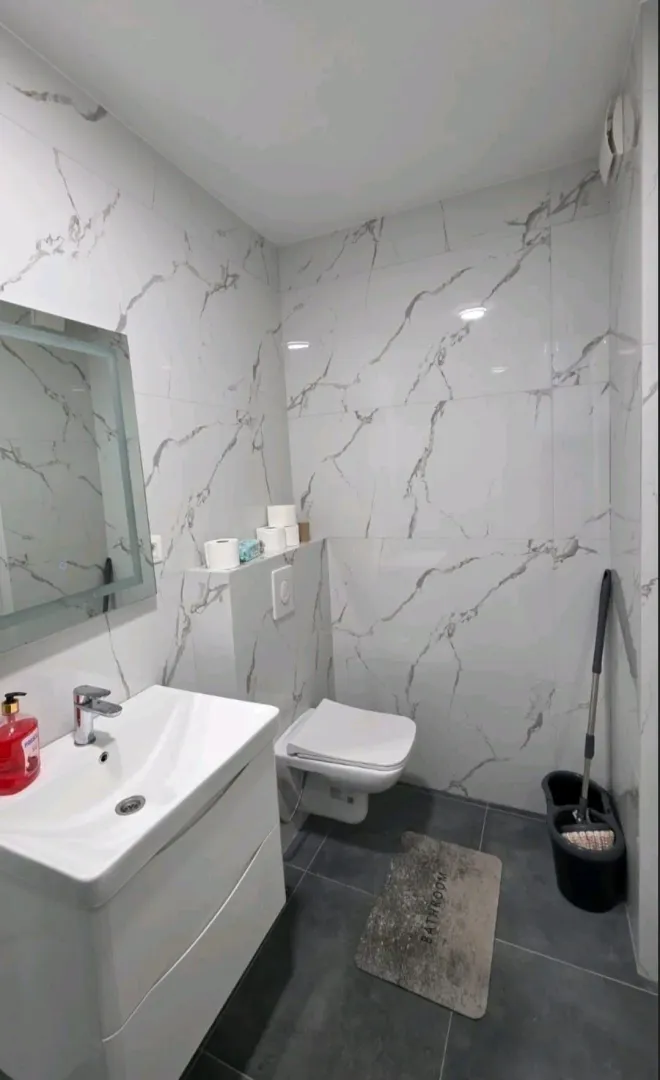 Moderne opremljeno kupatilo sa bijelim pločicama sa efektom mermera.