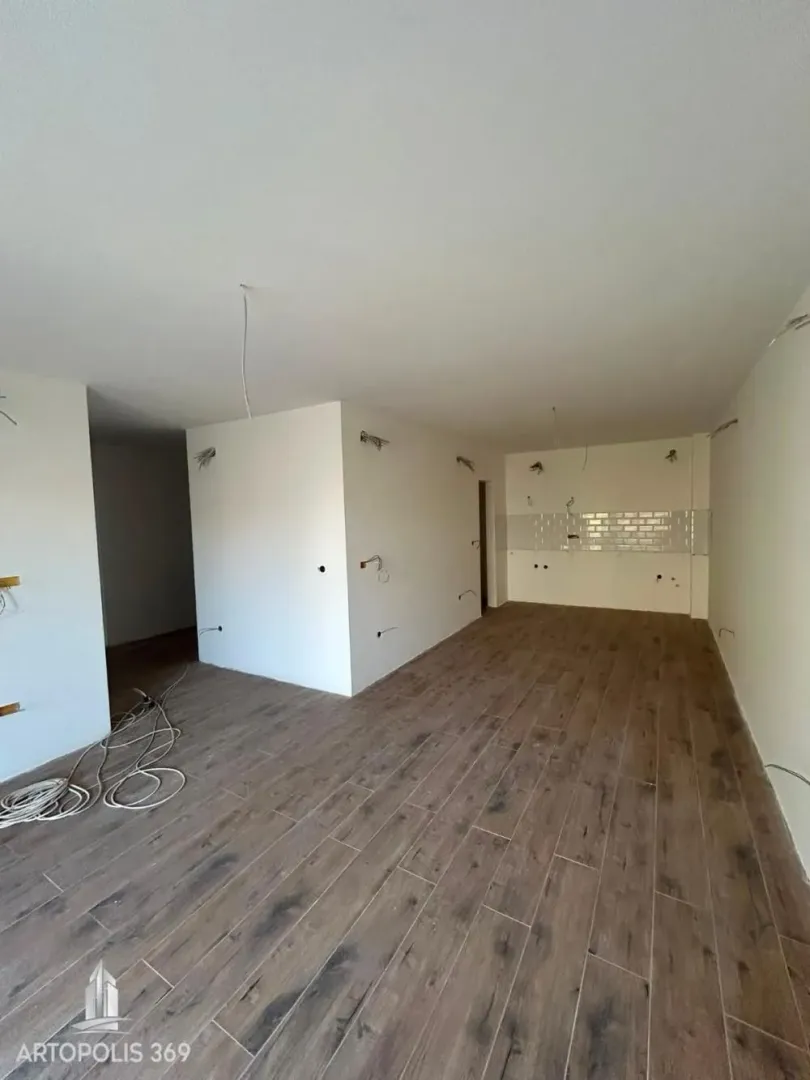 Neopremljen prostor u fazi renoviranja sa drvenim podovima i pripremljenim instalacijama za kuhinju.