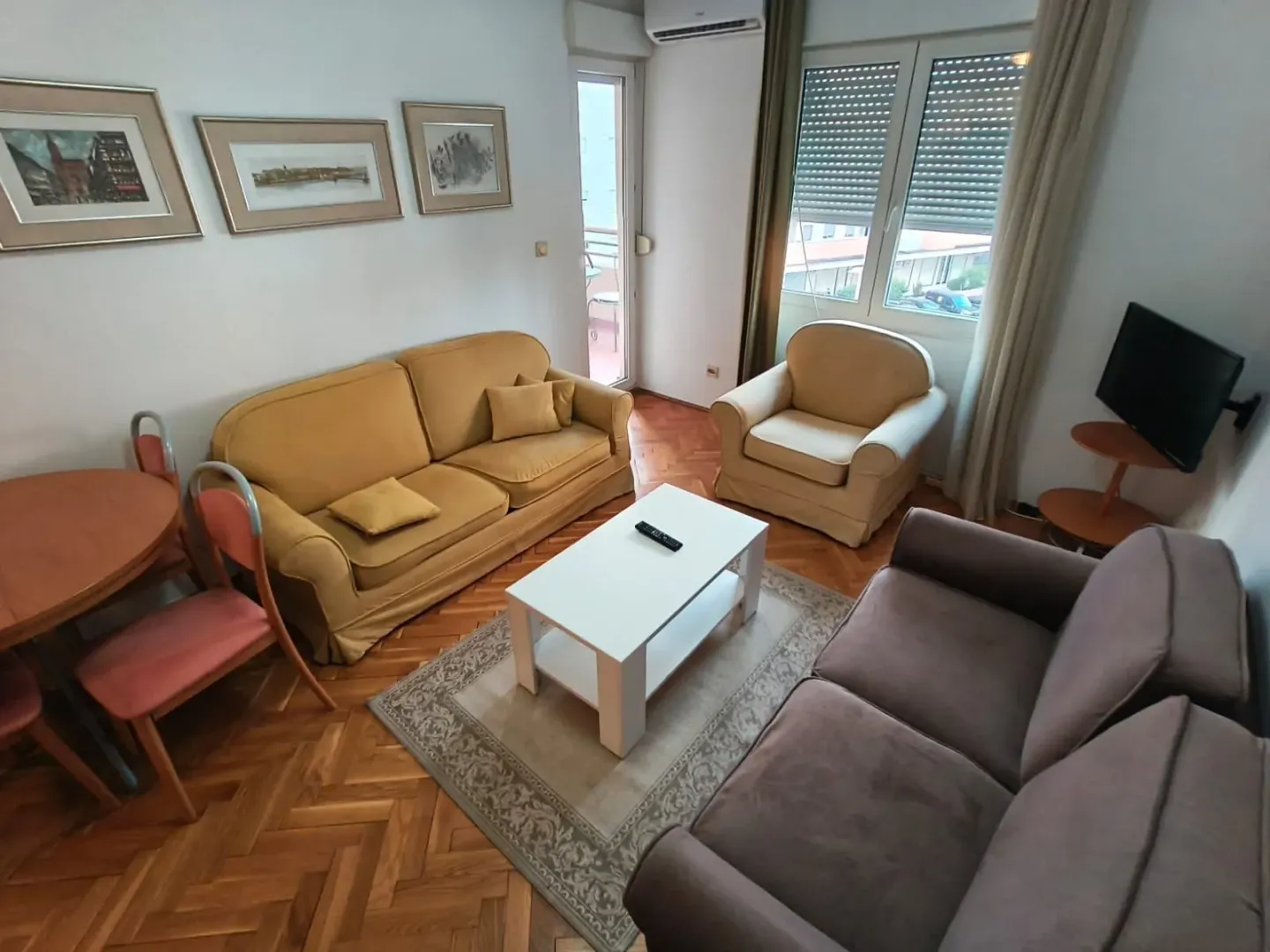 Dnevna soba sa garniturom za sedenje, stočićem i trpezarijskim stolom.