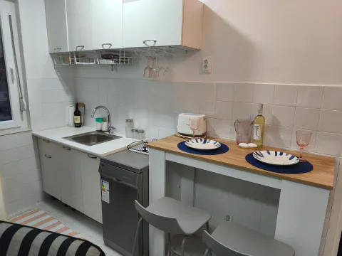 Mala kuhinja sa bijelim elementima, sudoperom i trpezarijskim stolom za dvoje. - image 3