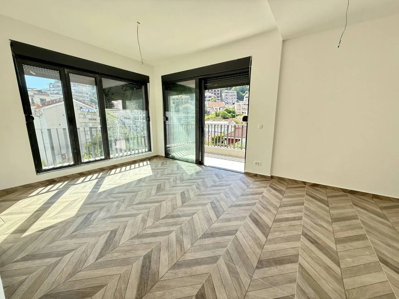 Empty room with wooden flooring and access to the terrace.