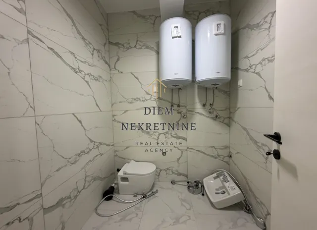 Bathroom under furnishing with sanitaryware and water heaters.