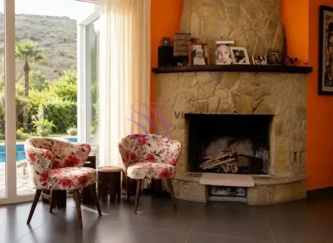 Living room with a stone fireplace and two armchairs next to a large glass window. - image 14