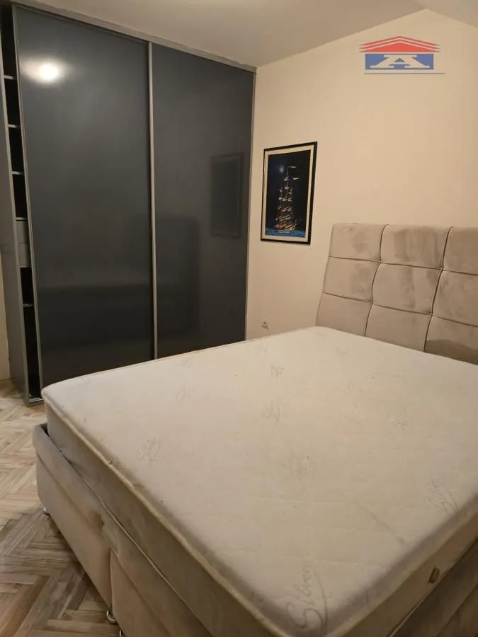 Nameštena spavaća soba sa bračnim krevetom i velikim ormanom.