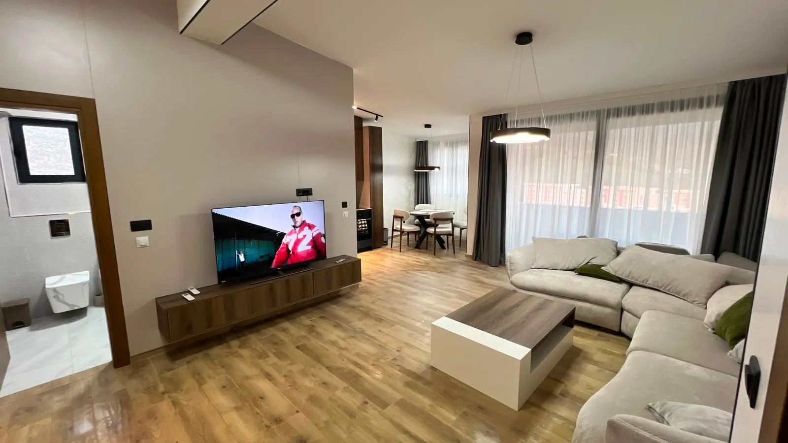 Spacious living room with a sofa and a dining area in the background.