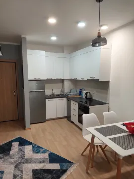 Modern kitchen with white units and a dining table. - image 3