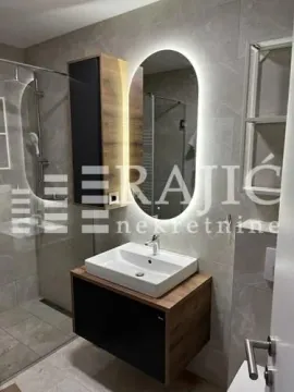 Modern bathroom with a washbasin, backlit mirror, and shower enclosure. - image 16
