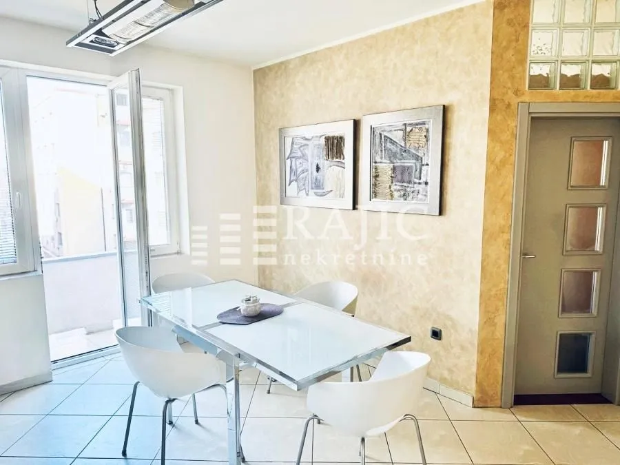 Dining area with a table, white chairs, and access to the terrace.