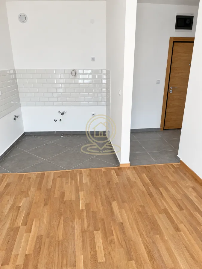 Nenamešten deo kuhinje sa keramičkim pločicama na zidu i podnim instalacijama.
