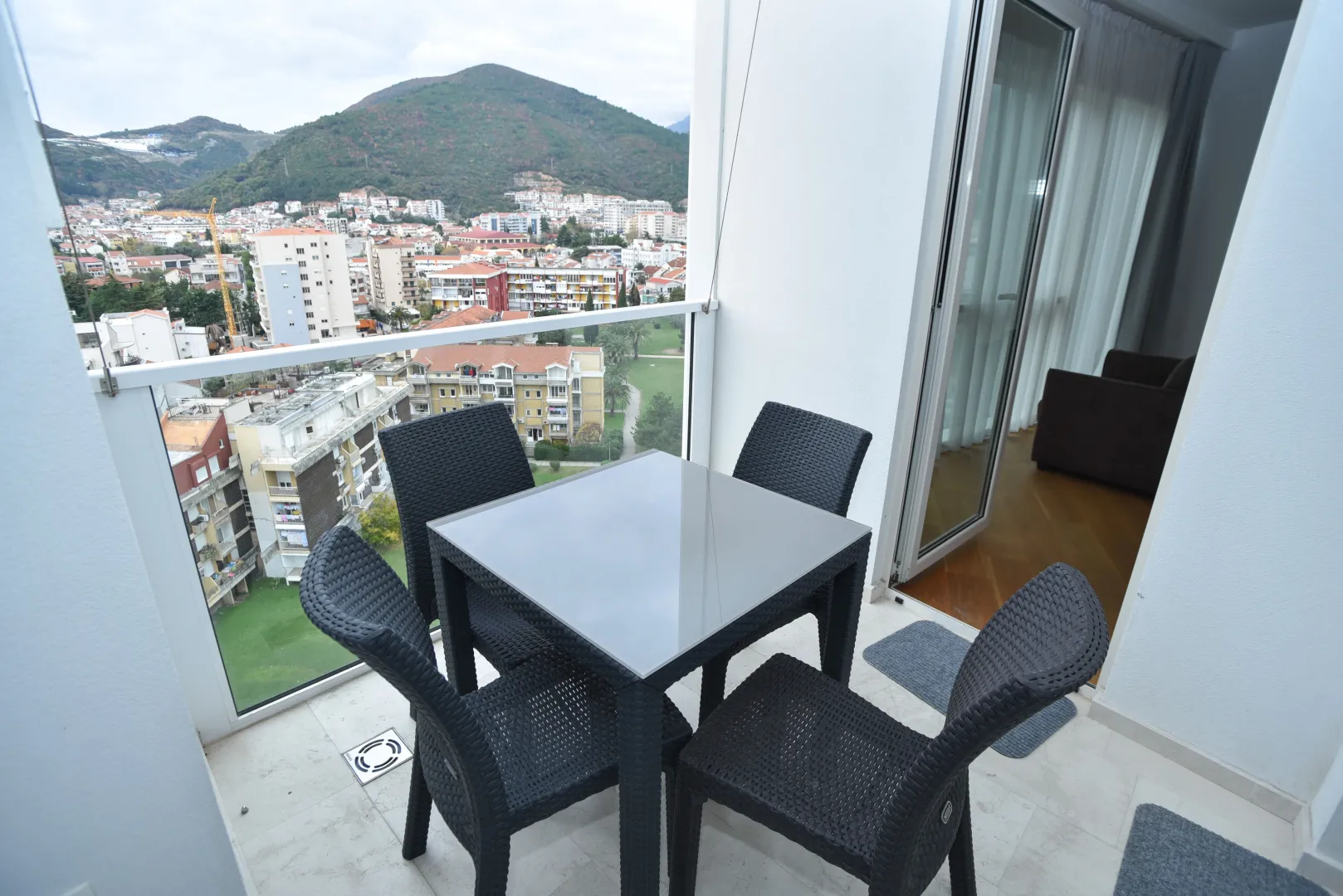 Furnished terrace with a table and chairs and a view of the city and hills.