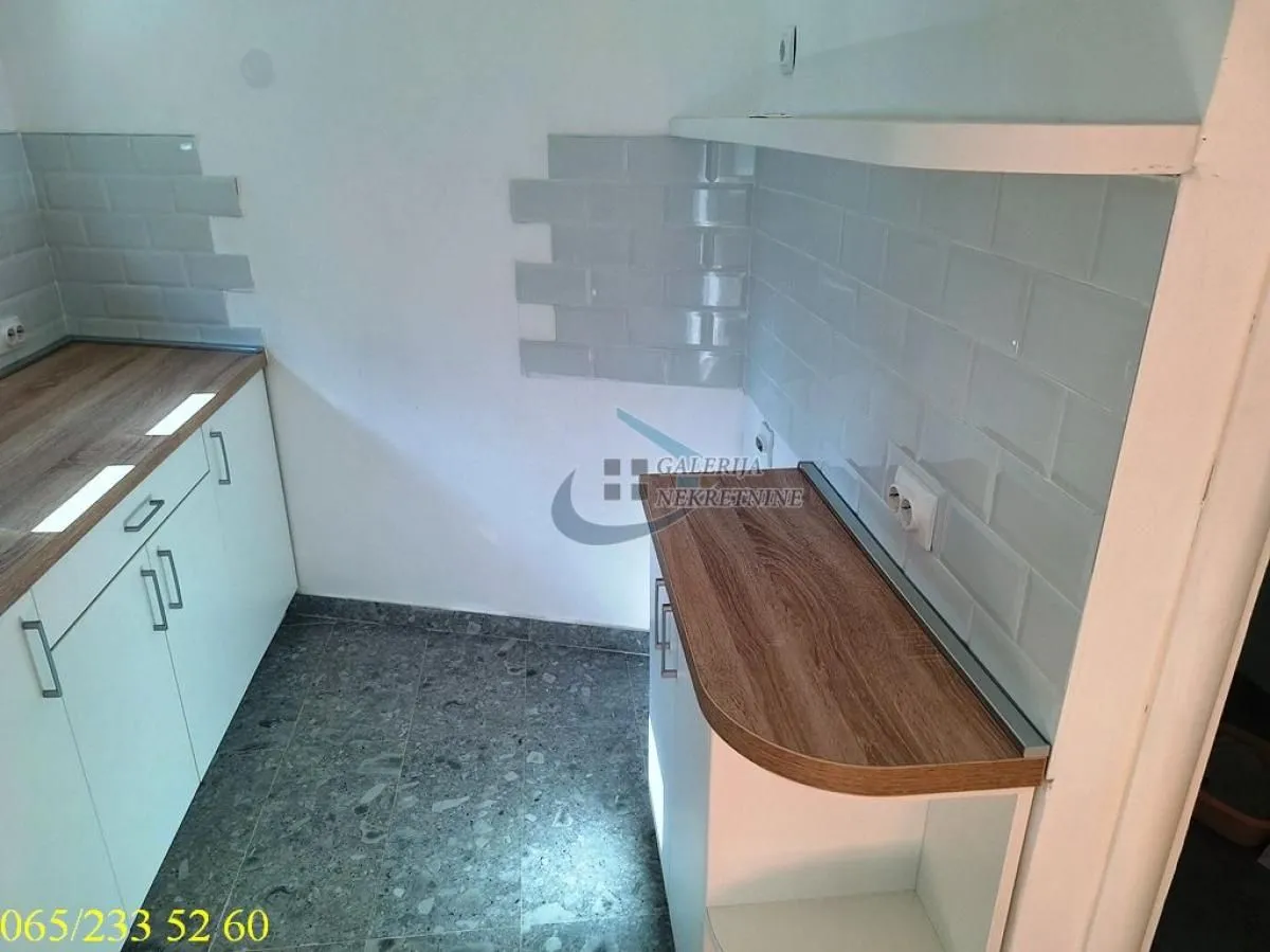Small kitchen with white cabinets and grey wall tiles.