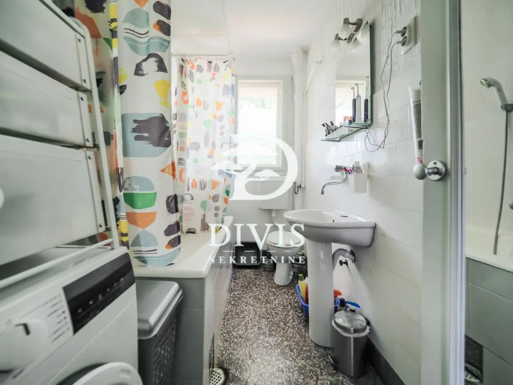 Smaller bathroom with a bathtub, washbasin, and washing machine.