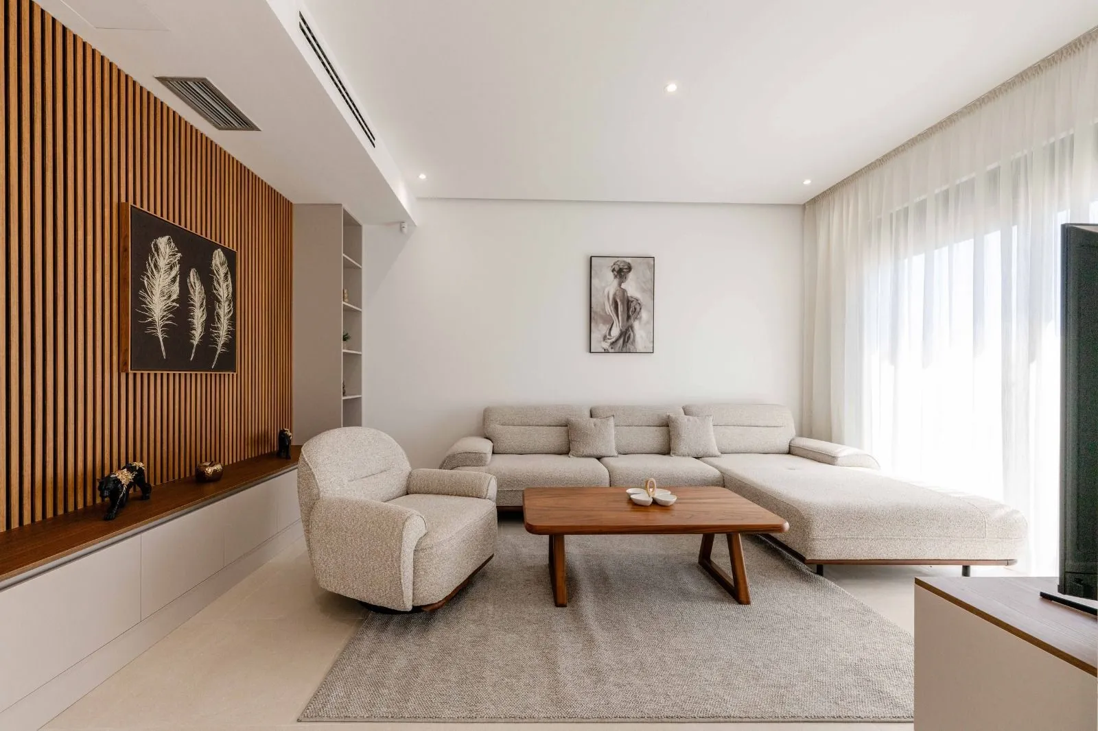 Modern living room with a sectional sofa, armchair, and wooden wall panels.
