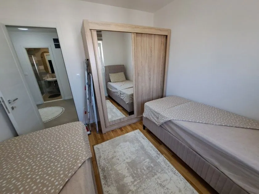 Namještena spavaća soba sa dva kreveta i ormarom.